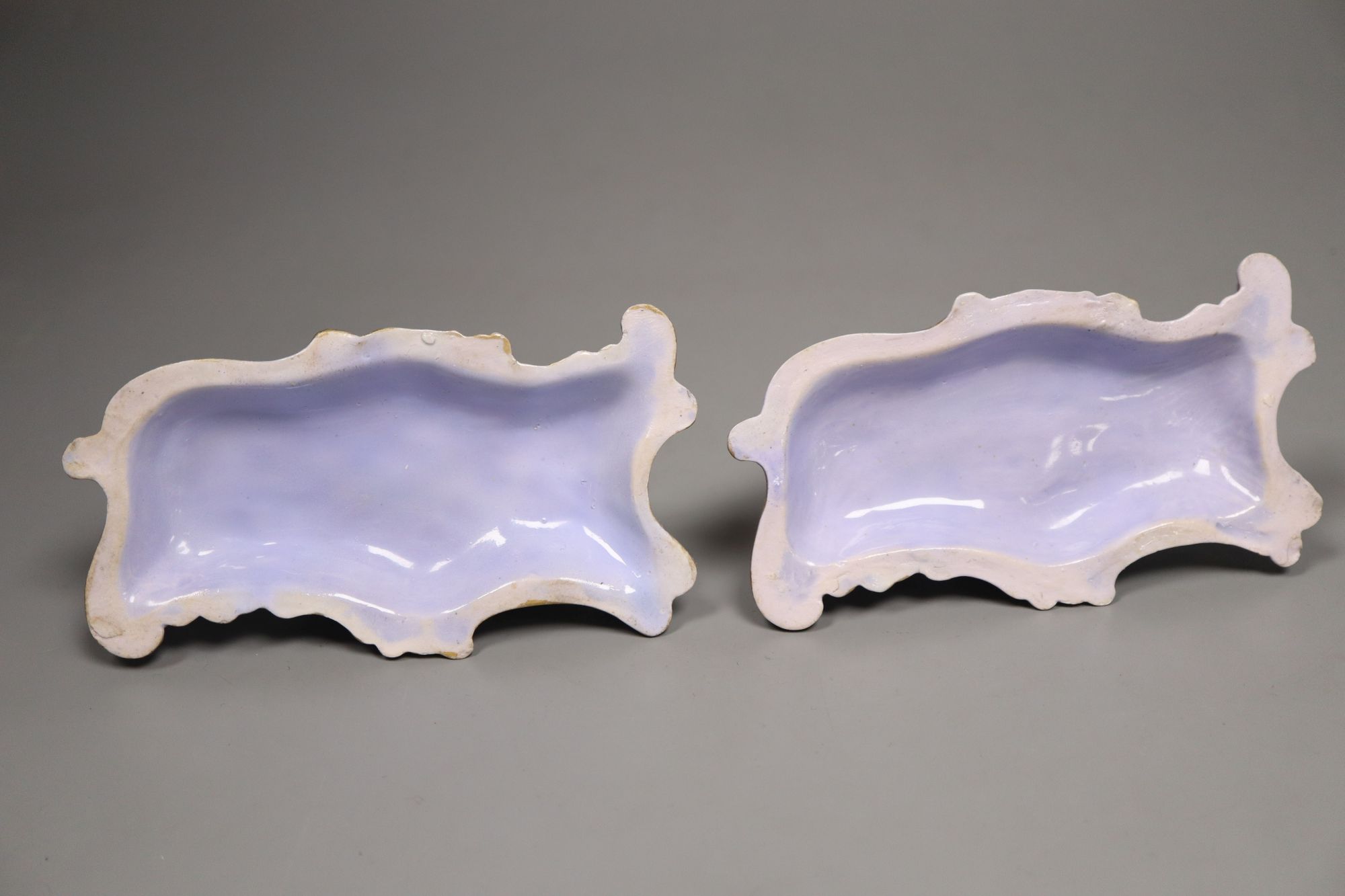 A good pair of Staffordshire porcelain figures of recumbent poodles, c.1835-50, 12.2cm long, lavender ground scrolled bases